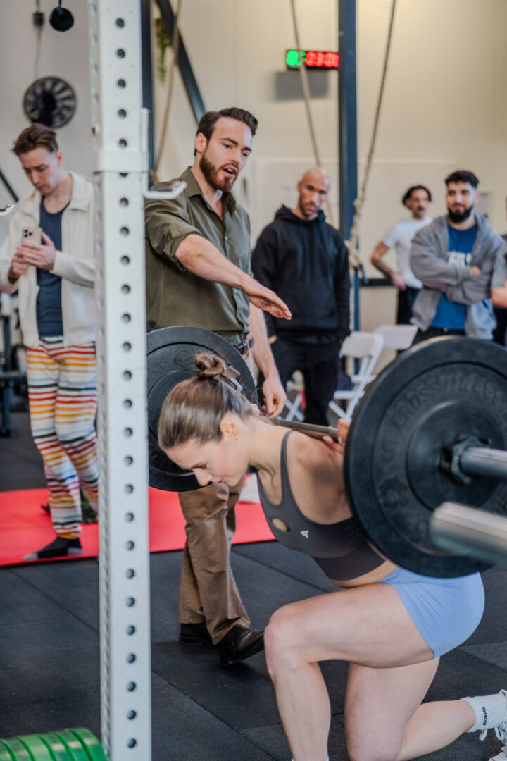 Menno Henselmans coaching a lifter through a barbell exercise at a live training meetup.