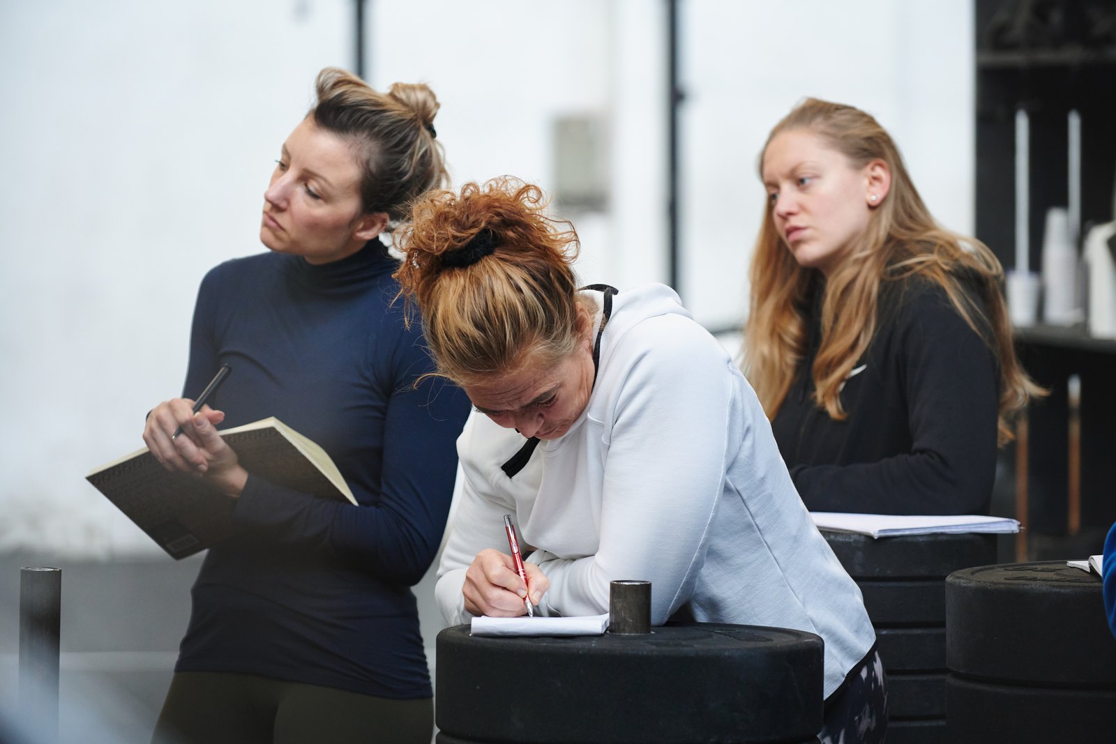 Drie cursisten maken aantekeningen tijdens een workshop van de cursus.